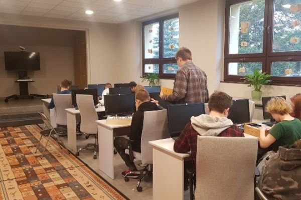 Uczniowie liceum siedzący przy stanowiskach komputerowych w sali bibliotecznej