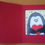 Czerwona kartka Walentynkowa. W środku pingwin trzymający w skrzydełkach czerwoneserduszko
