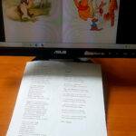 Na ekranie komputera bohaterowie "Kubusia Puchatka", na stoliku kartka z wierszami o sowach