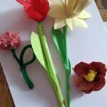 Prace plastyczne z warsztatów dla nauczycieli "Kwietna łąka DIY" - czerwony mak z bibuły, żółty narcyz z papieru, różowa koniczyna z włóczki i czerwony mak z wytłaczanki po jajkach.