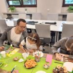Laureaci, razem z rodzicami, tworzą kolorowe zawieszki na drzwi