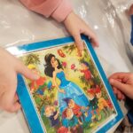 Przedszkolak pokazuje ułożone puzzle, które przedstawiają Królewnę Śnieżkę i siedmiu krasnoludków