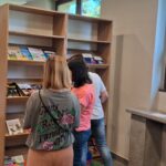 Nauczycielki przeglądają książki na półce z nowościami.