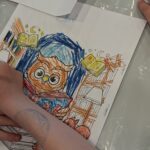 Dziecko koloruje ilustrację z sową w roli głównej.