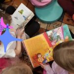 Dzieci siedzą na dywanie i przeglądają książeczki