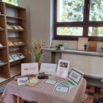 Na stole materiały promujące wydarzenie - Narodowe Czytanie "Dziadów" Mickiewicza. Na regale publikacje ze zbiorów Biblioteki poświęcone Mickiewiczowi.